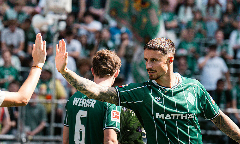 Marco Friedl klatscht ab, im Hintergrund Jens Stage.