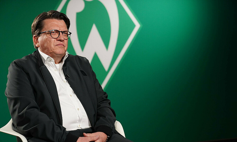Hubertus Hess-Grunewald im Interview vor einer Werder-Raute. 