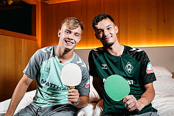  Mio Backhaus und Keke Topp halten zwei Tischtennisschläger in der Hand.