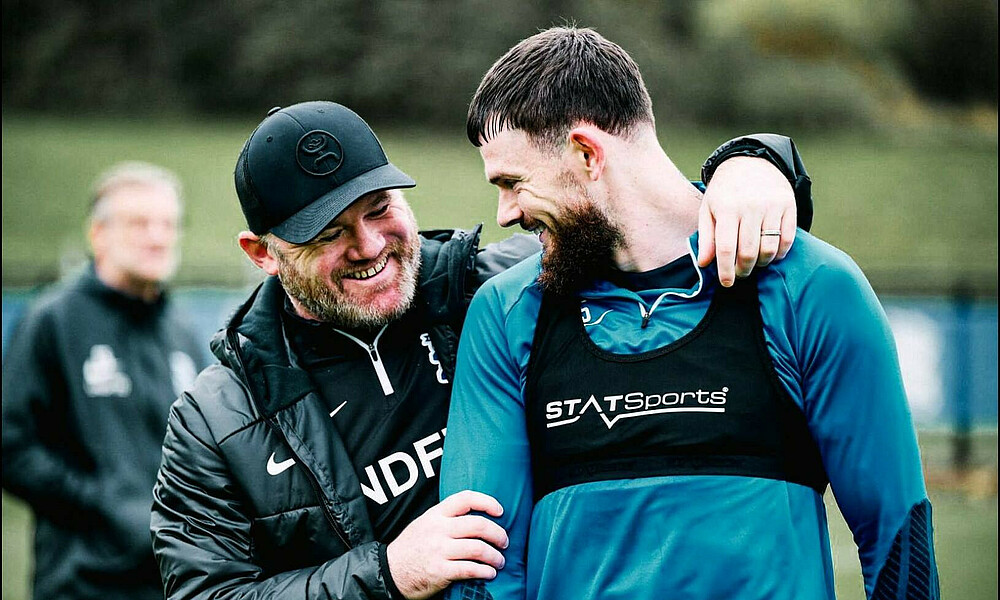 Wayne Rooney und Oliver Burke Arm in Arm. 