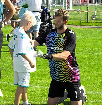 Felix Wiedwald unterschreibt das Trikot von einem Fan. 