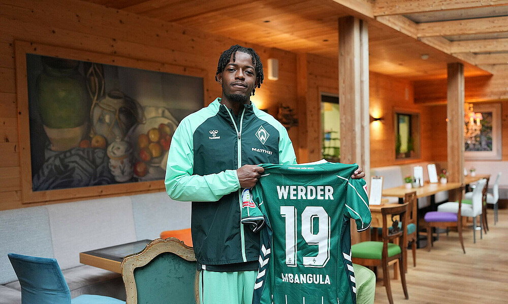 null Mbangula präsentiert sein Trikot im Mannschaftshotel.
