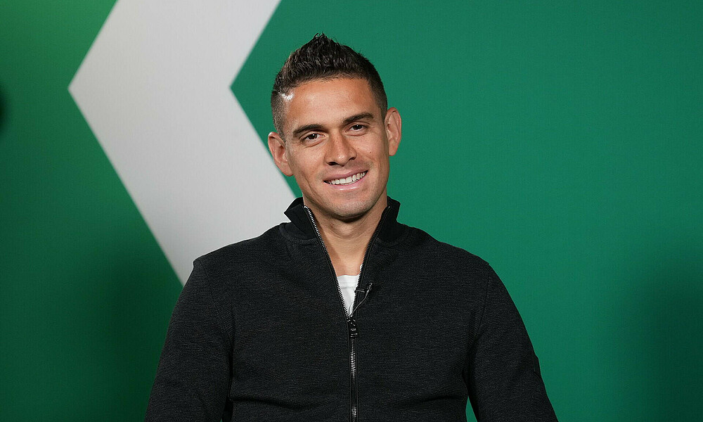 null Rafael Borré sitzt vor einer grünen Wand.