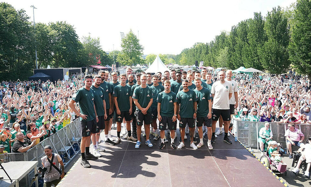 Im Vordergrund die Spieler auf der Bühne, im Hintergrund die Fans.