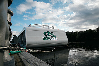 Die Grüne Bude im Wasser bei blauem Himmel.