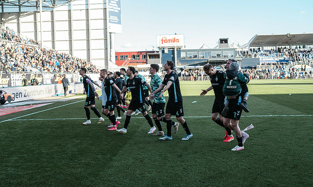 Werder-Spieler jubeln im Ausweichtrikot vor dem Gästeblock in Kiel