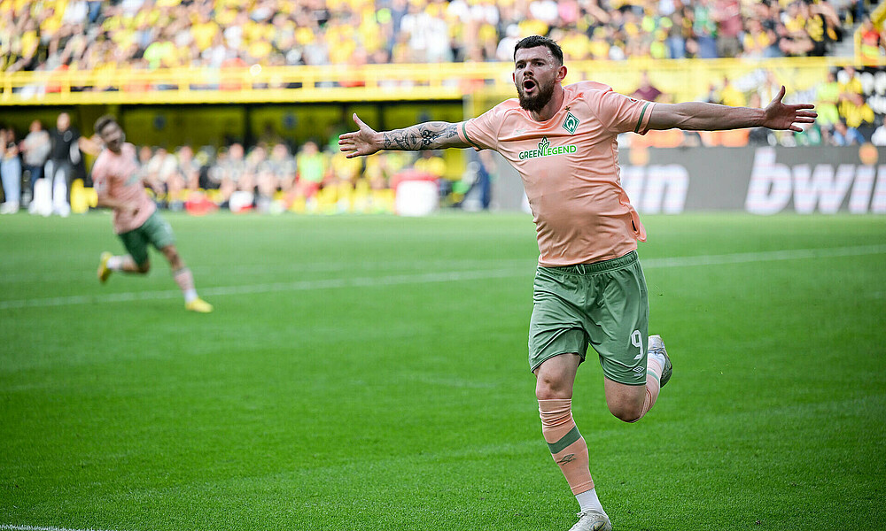 Burke jubelt mit ausgebreiteten Armen. 