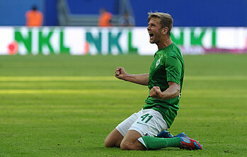 Niclas Füllkrug rutscht im Werder-Trikot auf Knien über den Rasen.