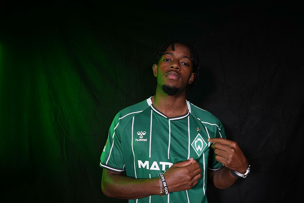 Samuel Mbangula zeigt auf sein Trikot. 