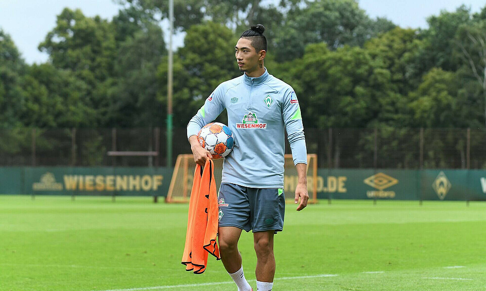 Kyu-hyun Park geht mit Trainingsutensilien vom Trainingsplatz.