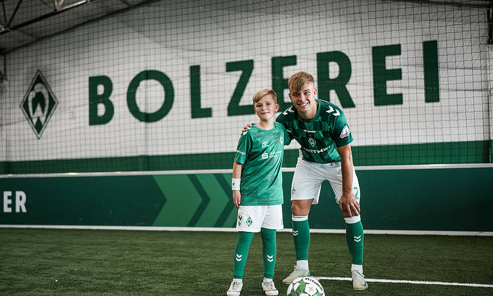 null Keke Topp steht mit einem Kind auf einem Fußballplatz in der BOLZEREI