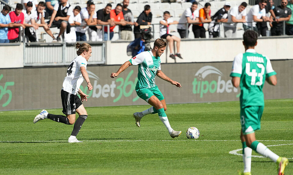 Niclas Füllkrug läuft mit dem Ball, verfolgt von einem Gegenspieler.