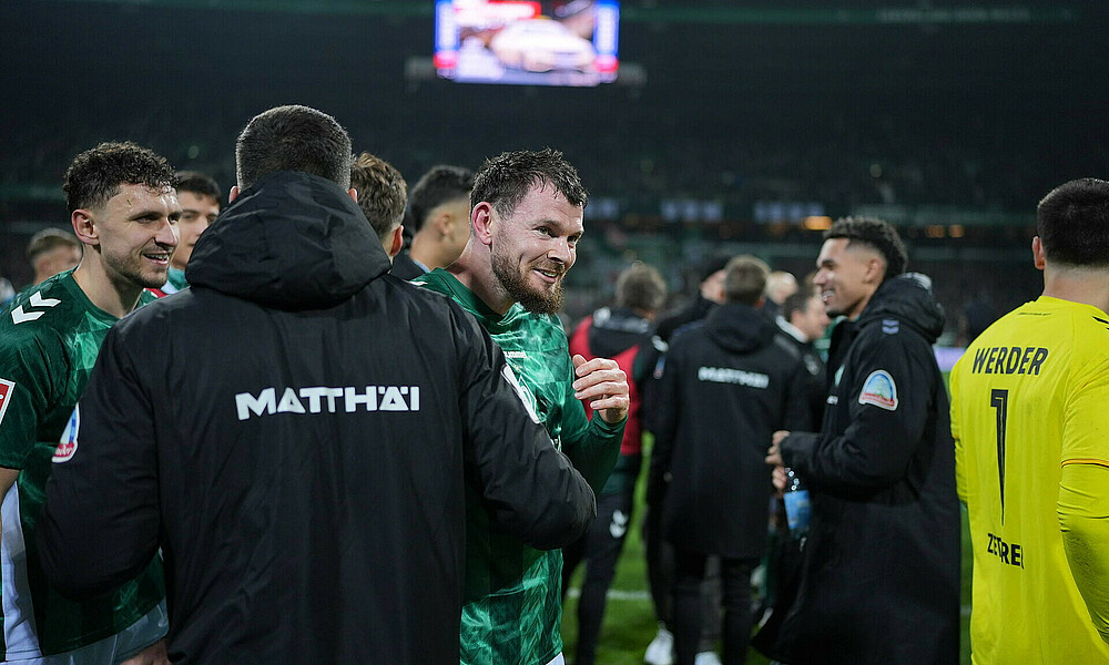 Oliver Burke wird von seinen Mitspielern nach dem Abpfiff und dem 2:1 gegen Holstein Kiel geherzt