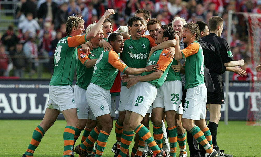 null Werder-Spieler jubeln in einer Traube.