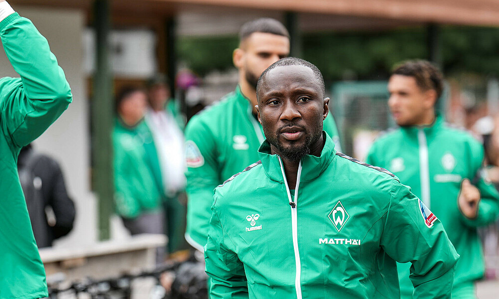 Naby Keïta in Trainingskleidung. Er trägt eine grüne Regenjacke.