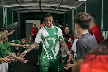 Marco Friedl läuft durch den Spielertunnel und klatscht die Einlaufkinder ab.