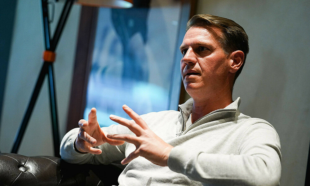 Tim Borowski in einem Sessel, er erklärt gerade. 