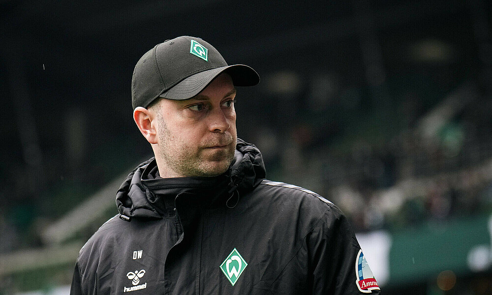 Ole Werner mit einer Cap auf dem Weg über den Platz. 