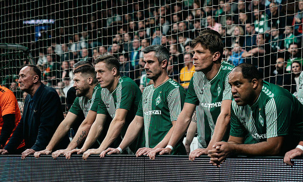 Spieler der Traditionsmannschaft schauen beim Spiel zu.