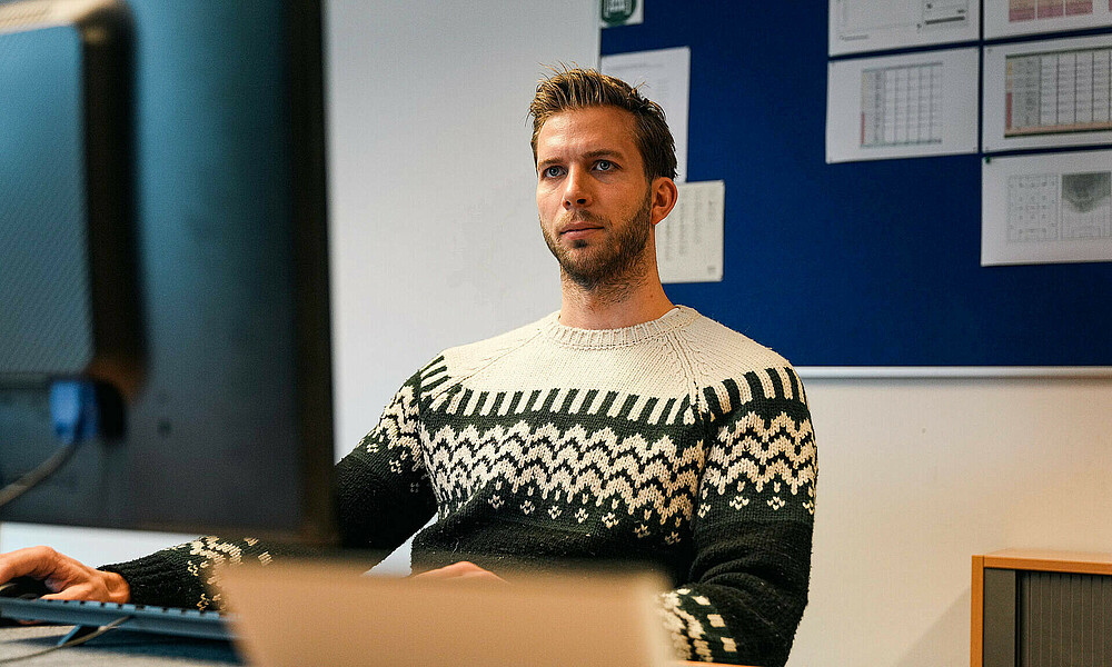 null Felix Wiedwald an seinem Schreibtisch an einem Rechner.