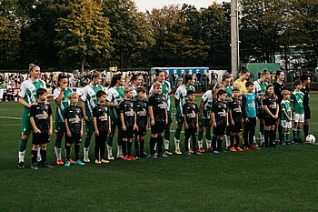 Die Werderfrauen stehen auf dem Rasen, vor den Spielerinnen stehen die Einlaufkinder.