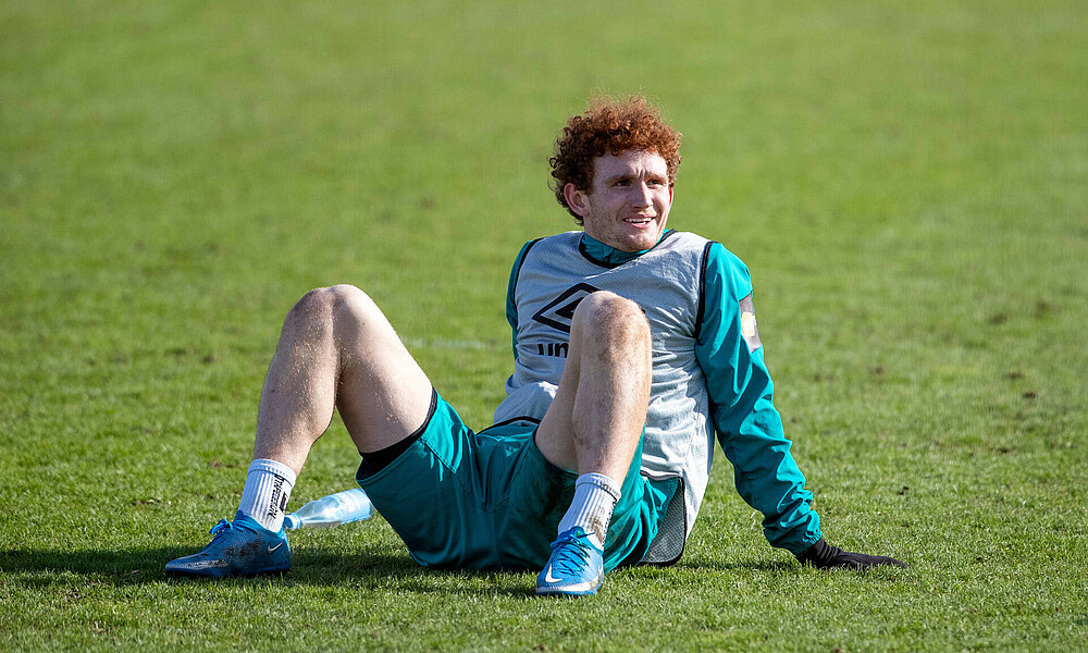 Josh Sargent sitzt nach dem Training auf dem Rasen.