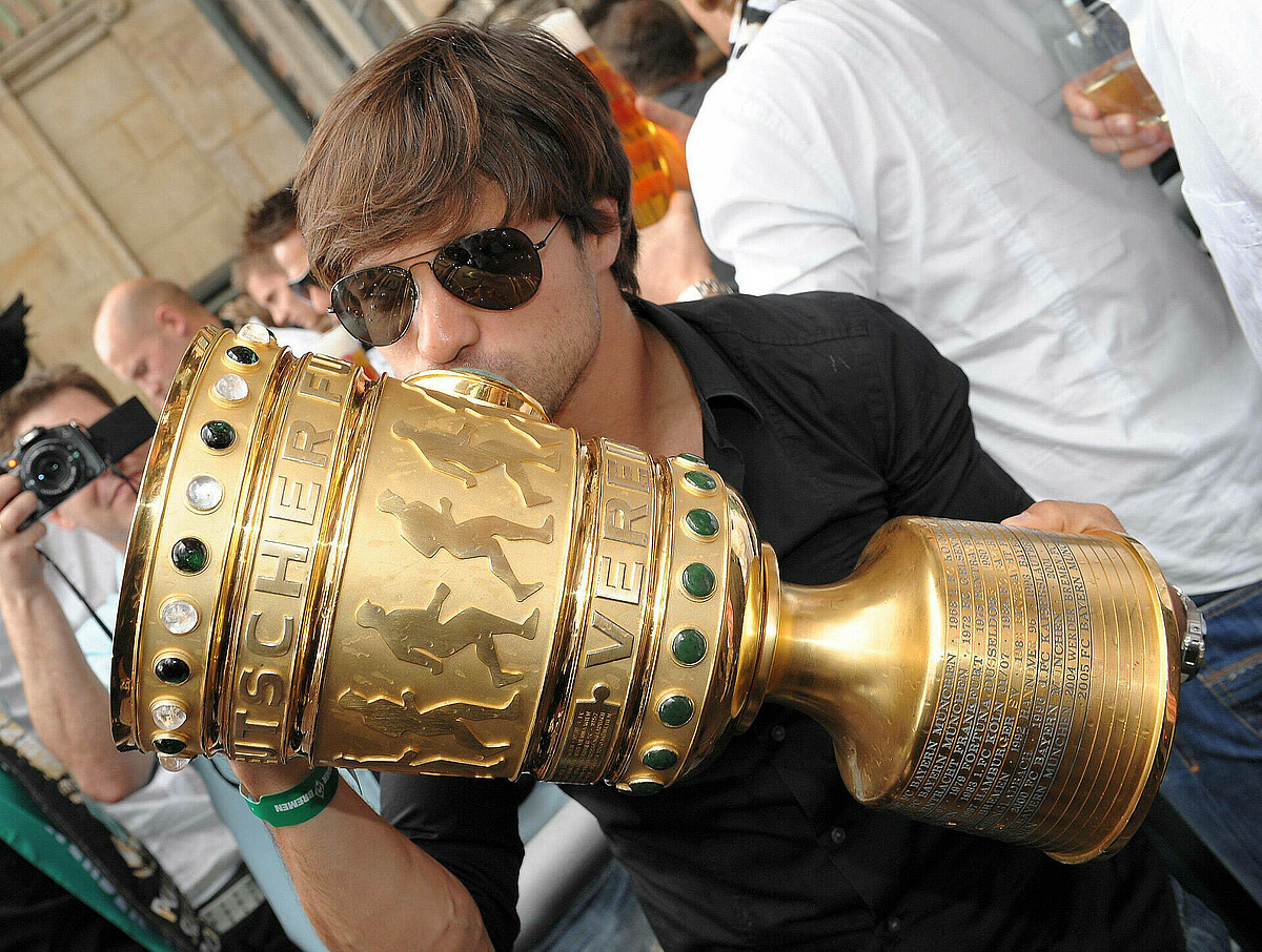 Diego küsst den DFB-Pokal, den er in der Hand hält.