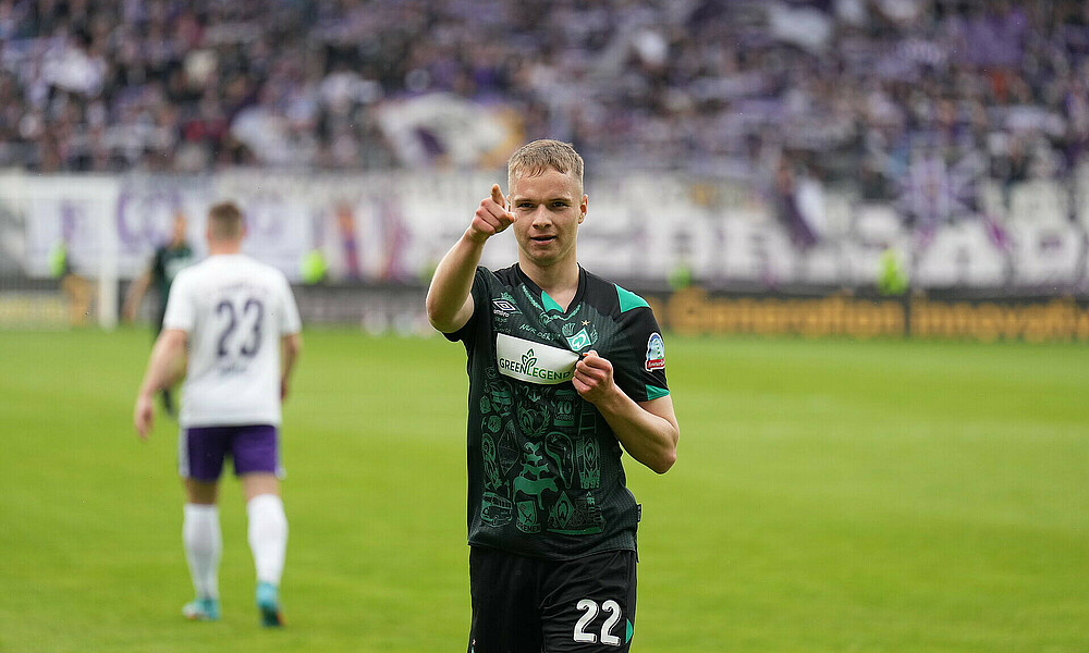 Werder-Spieler Niklas Schmidt streckt den Zeigefinger aus und hält mit der anderen Hand die Werder-Raute in der Hand.