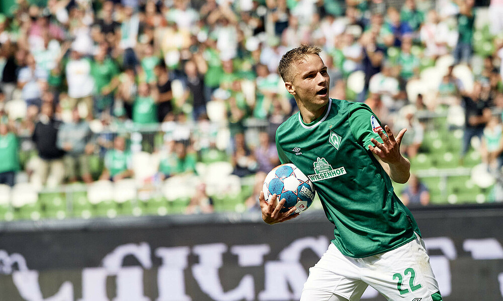 Niklas Schmidt jubelt mit einem Arm in die Luft gestreckt, unter dem anderen Arm hält er den Ball.