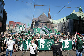 null Viele Fans gehen mit Fahnen hinter einem Banner mit der Aufschrift WERDER.