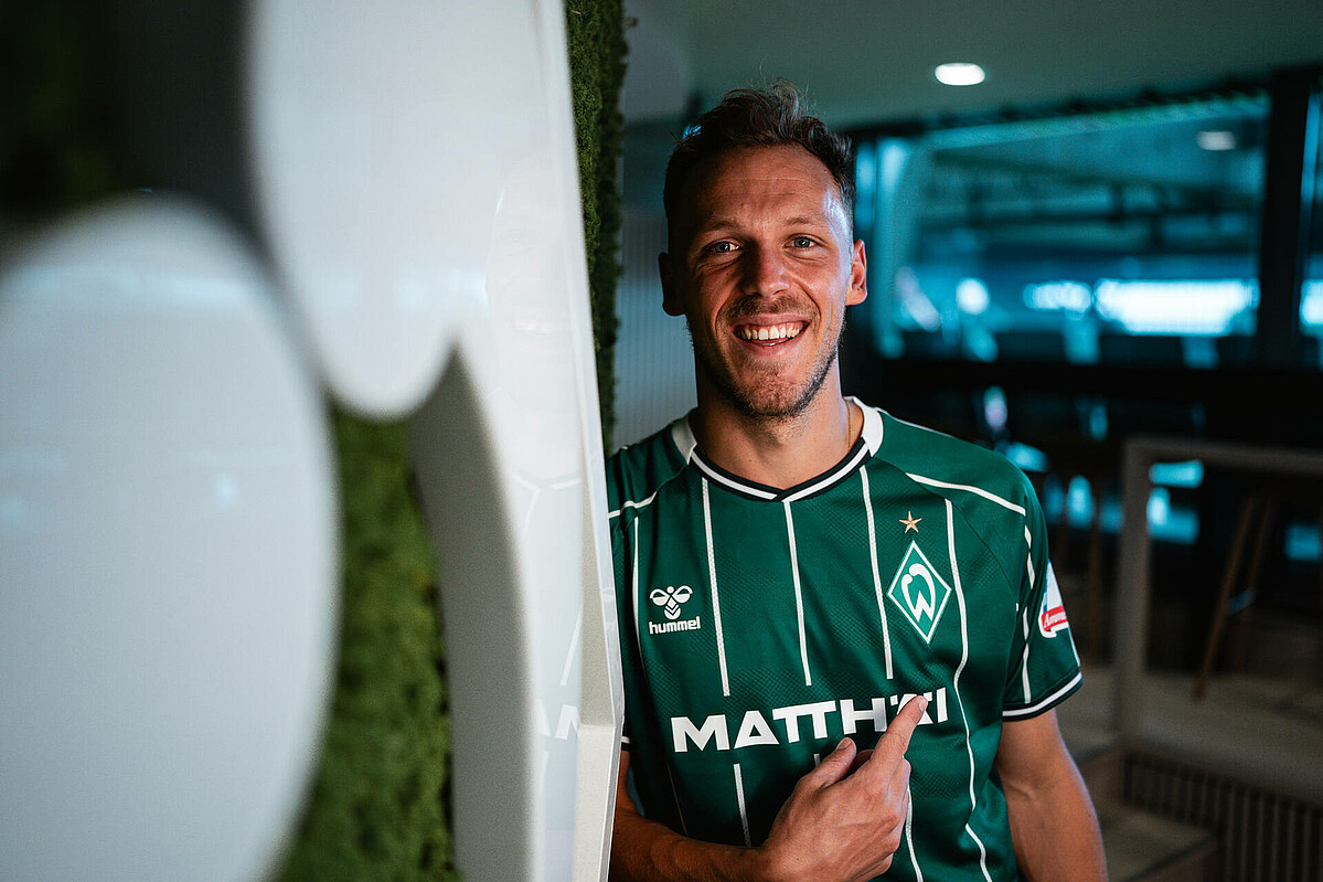 null Senne Lynen zeigt auf das Werder-Logo.