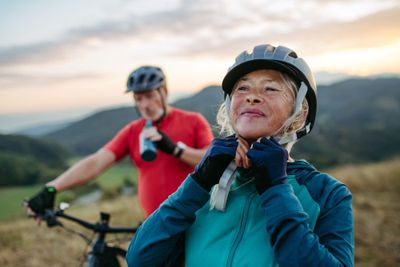 Silver economy: fitte ältere Frau mit älterem Mann mountainbiken