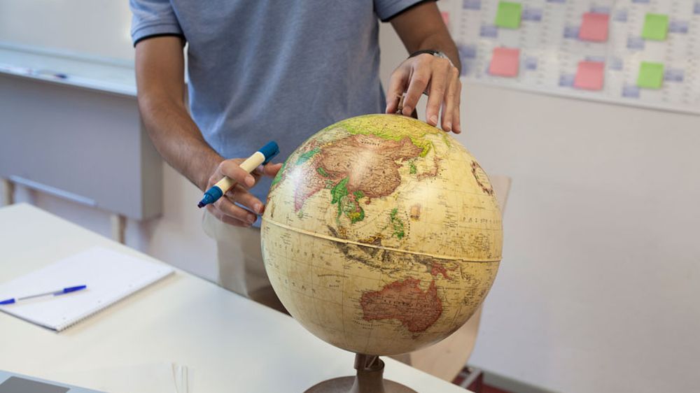 Vor- und Herausforderungen des globalen Handels Mann erkundet verschiedenste Routen des globalen Handels auf einem Globus