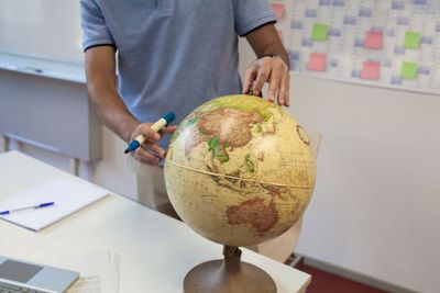 Mann erkundet verschiedenste Routen des globalen Handels auf einem Globus
