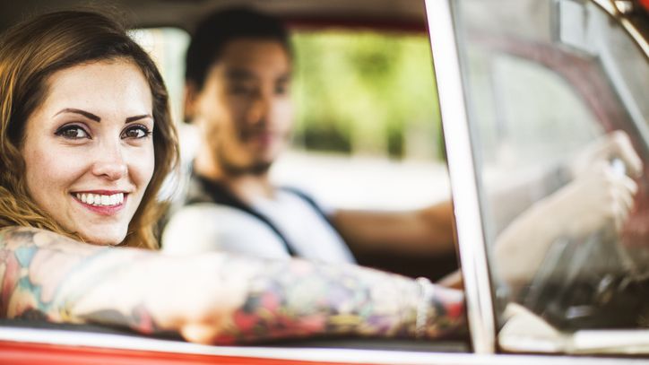 Junge Frau fährt mit Mann im roten Oldtimer