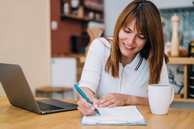uarterly distributions with Raiffeisen Global Income Funds: Woman sitting with laptop and writing materials, planning