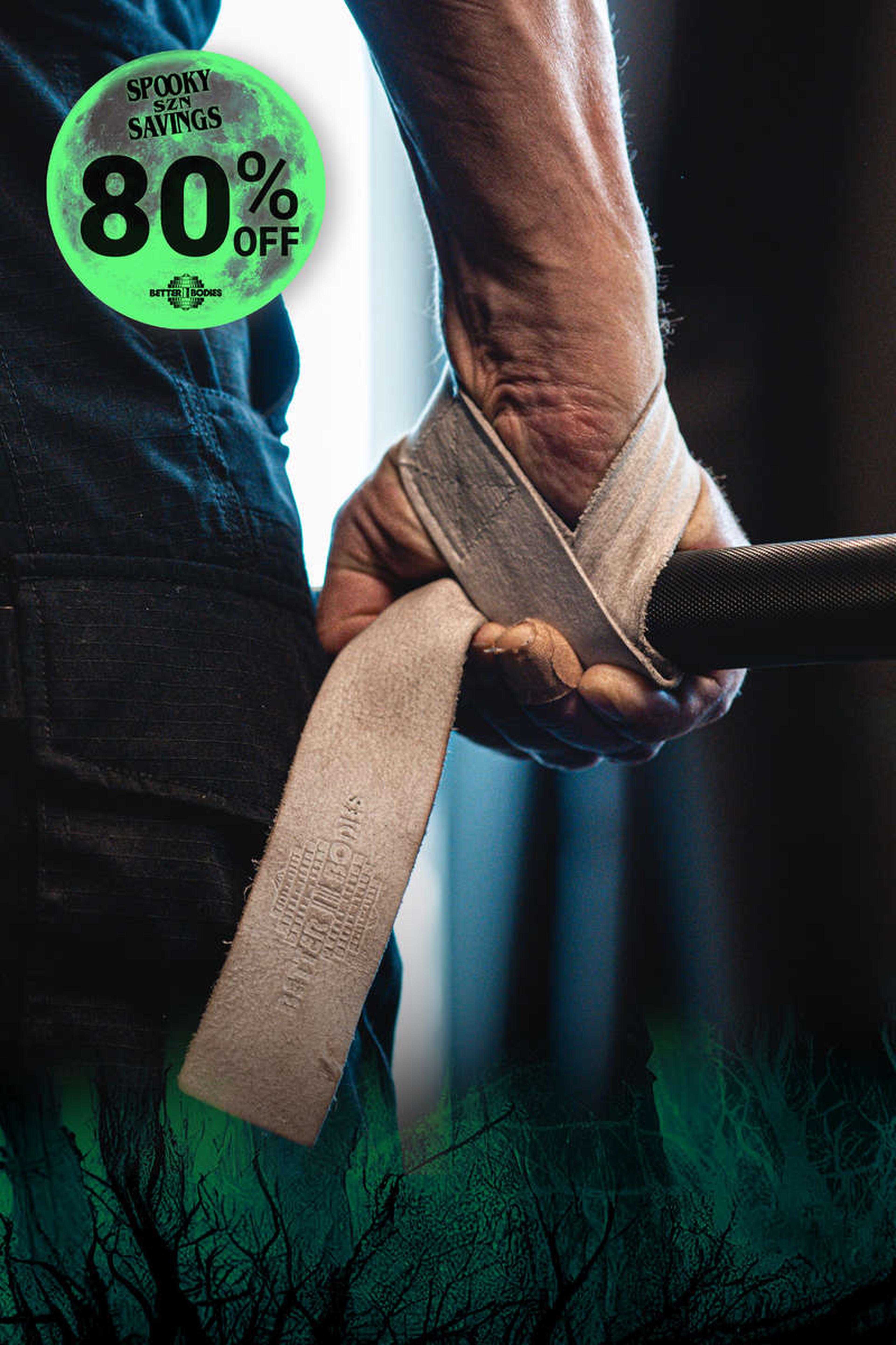 Close-up of a hand wrapping a wrist strap around a barbell. A green "Spooky Savings 80% Off" graphic is in the top left corner.
