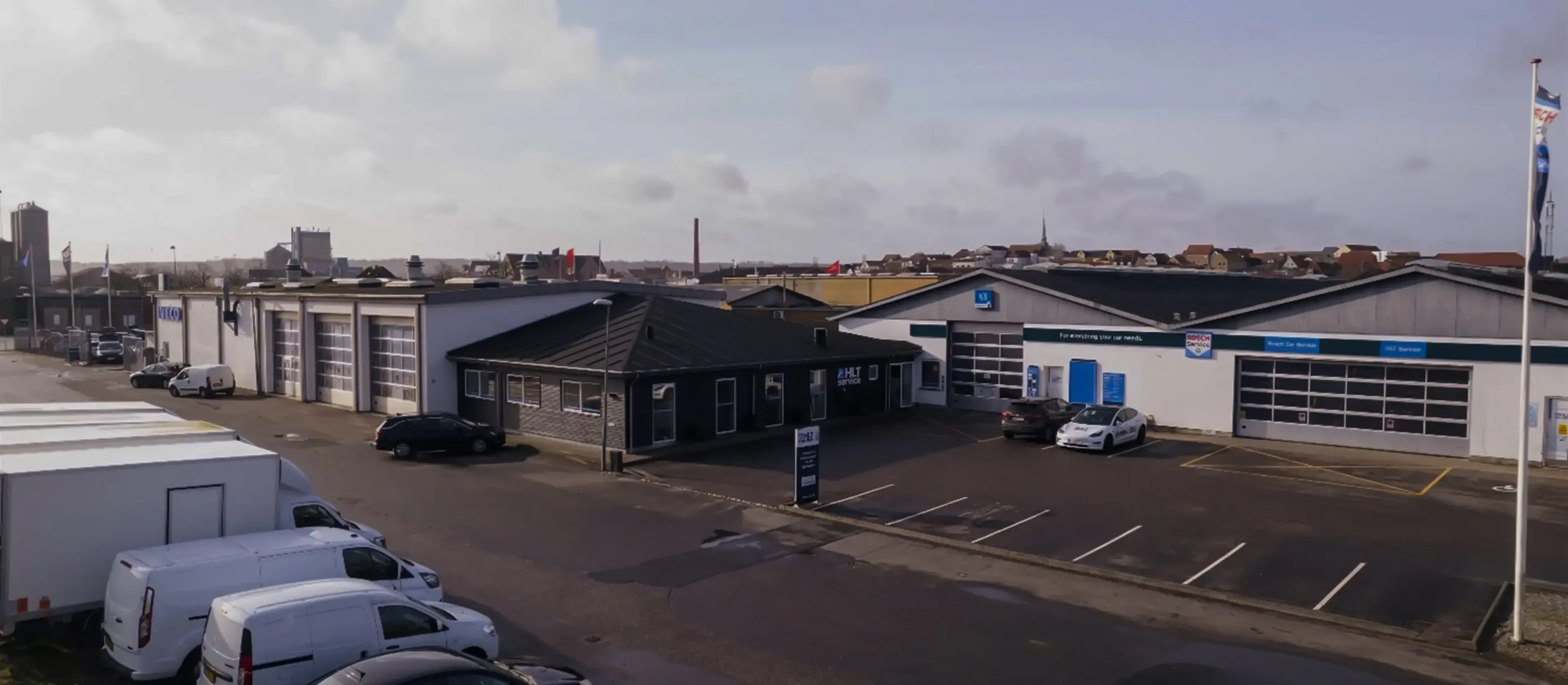 The Oscar Car Rental department in Aabenrå with parked Oscar Car Rental vans and cars in a paved lot under a cloudy sky.