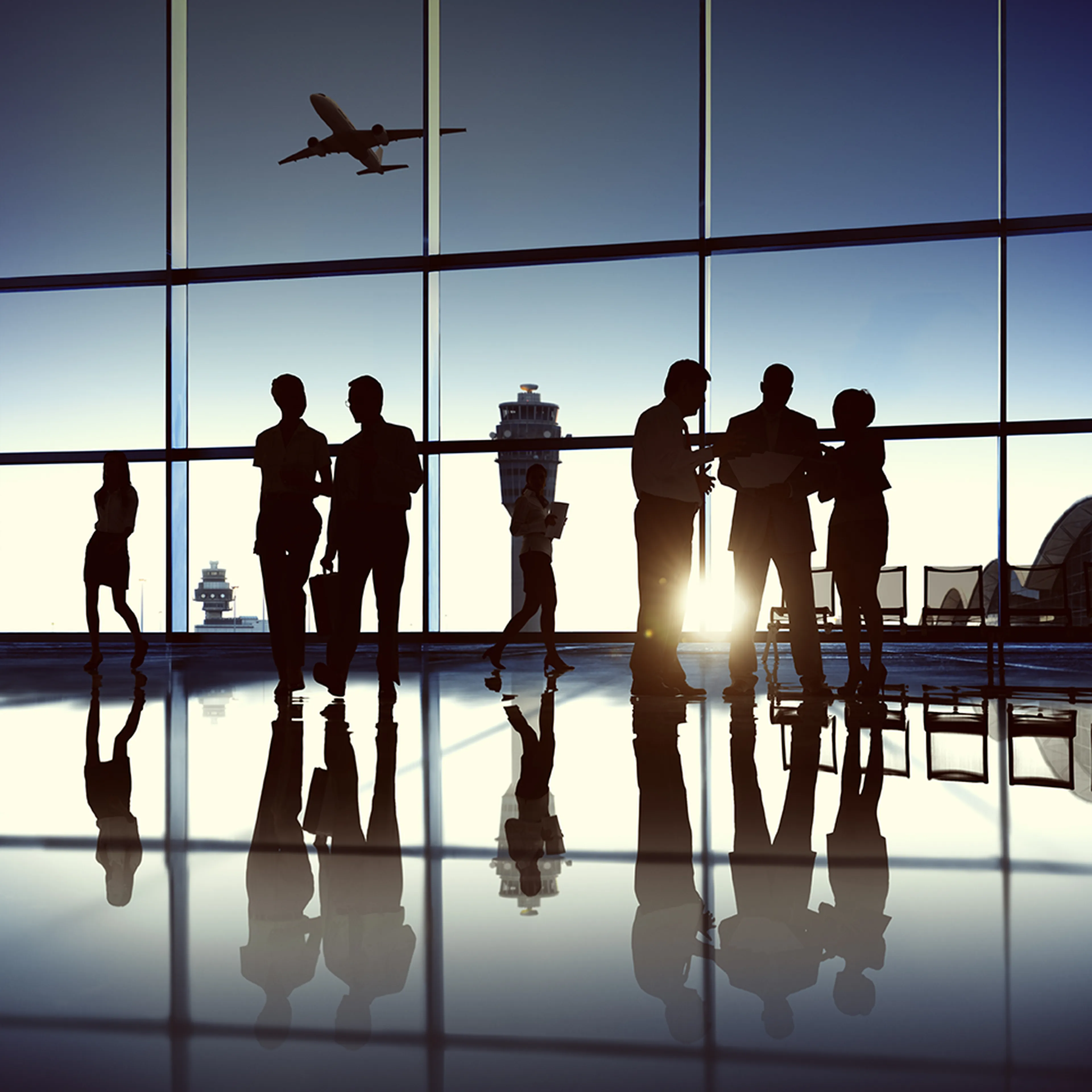 Silhouetted people conversing in an airport terminal with large windows, as an airplane takes off in the sky, reflecting on the shiny floor.