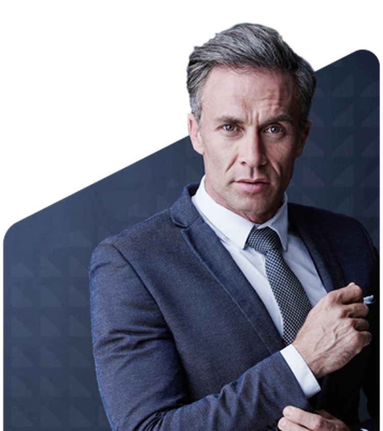 Man in a suit and tie stands confidently against a dark geometric background, holding a pen with a serious expression.