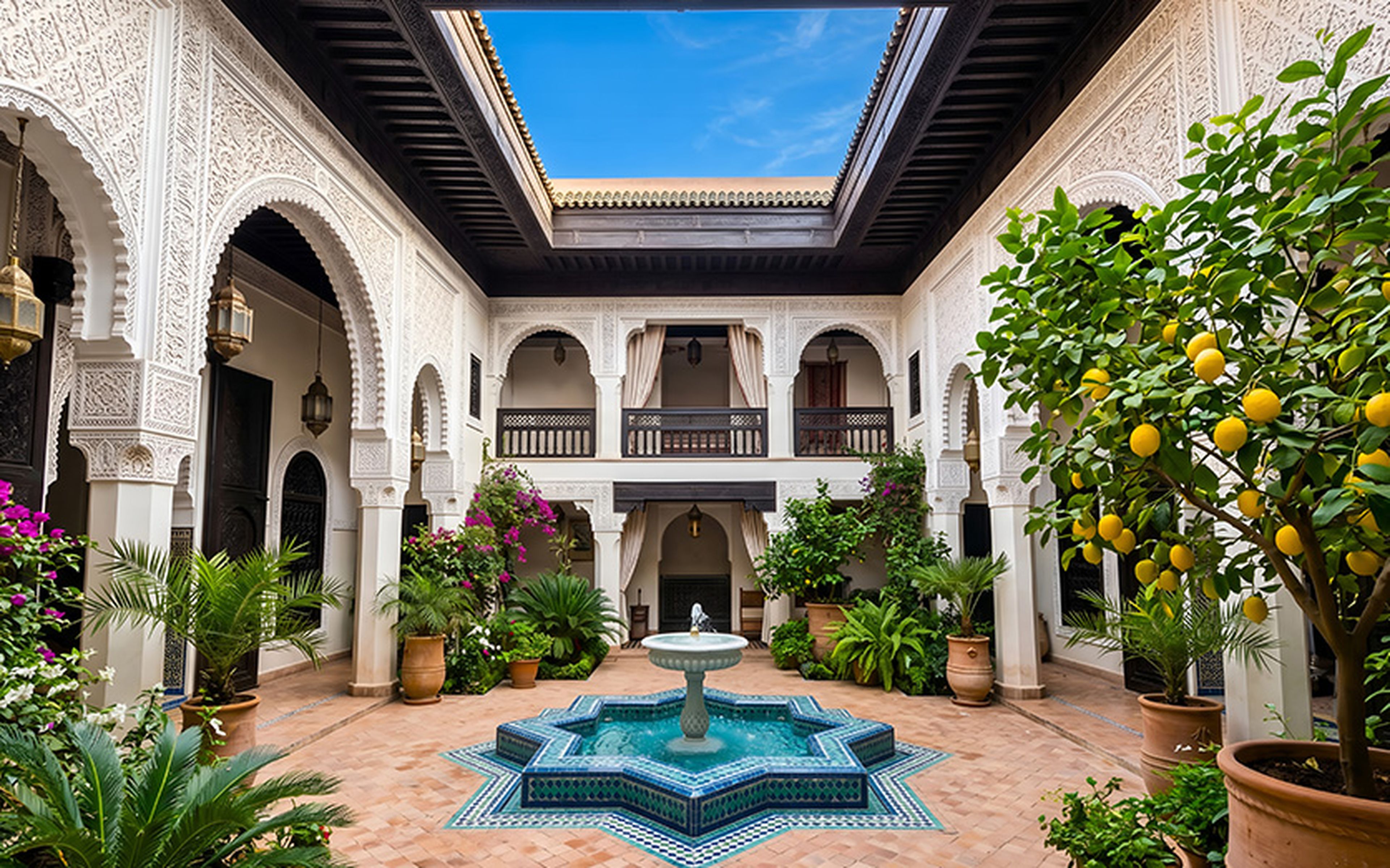 Elegant riad courtyard in Morocco with ornate white design and a central star-shaped fountain, surrounded by lush plants and a lemon tree.