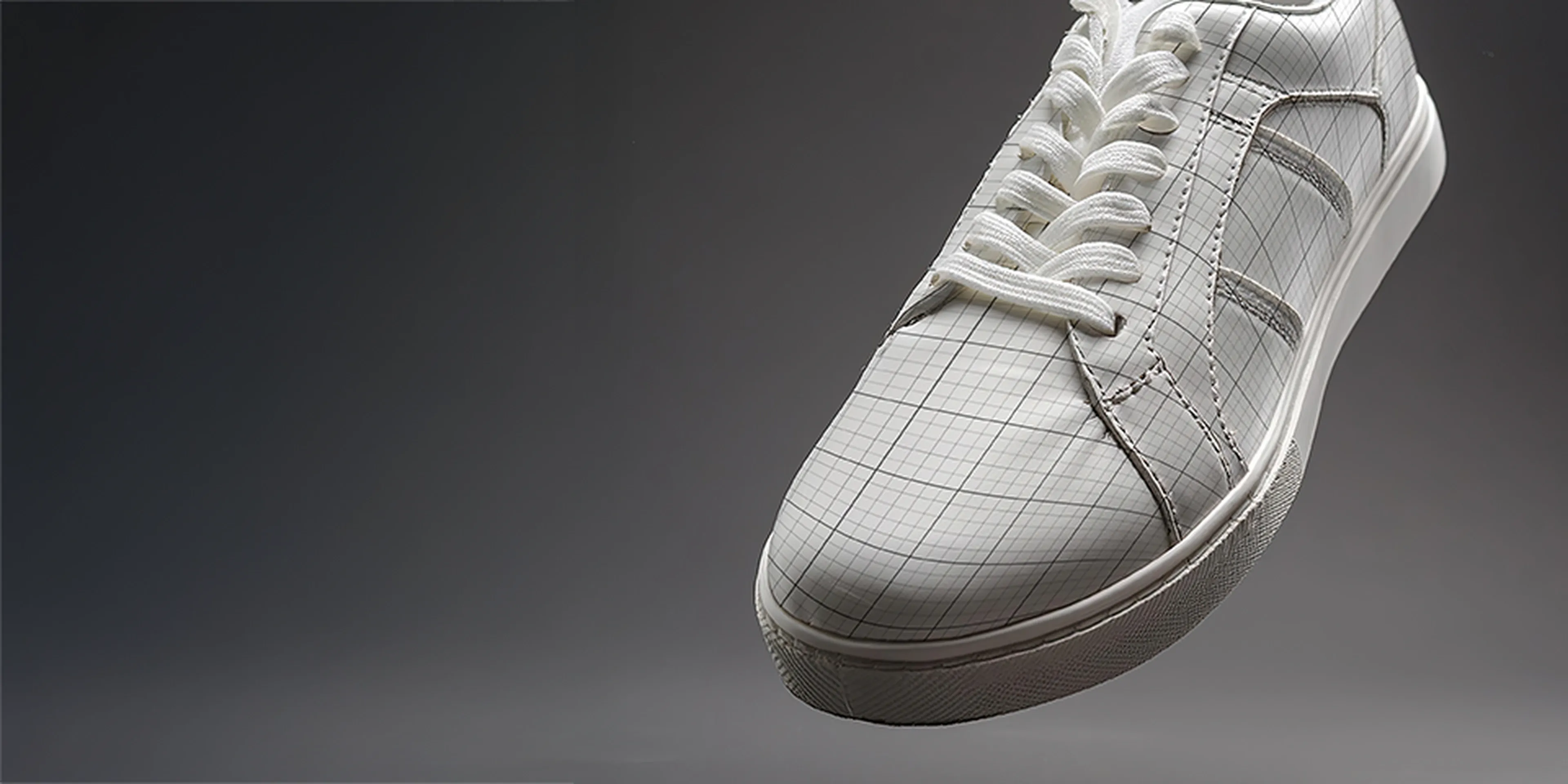 White sneaker with a grid pattern on the toe and sides, featuring white laces, set against a dark gradient background.