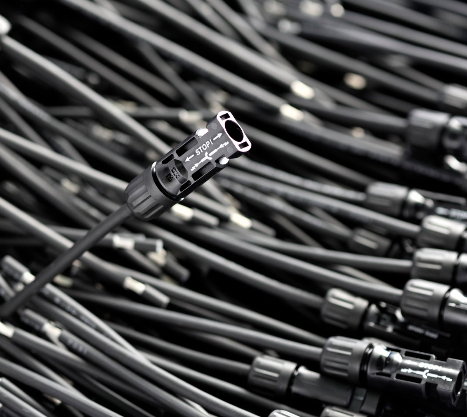 A close-up of a black HISKon electric cable with a connector against a blurred background of multiple cables