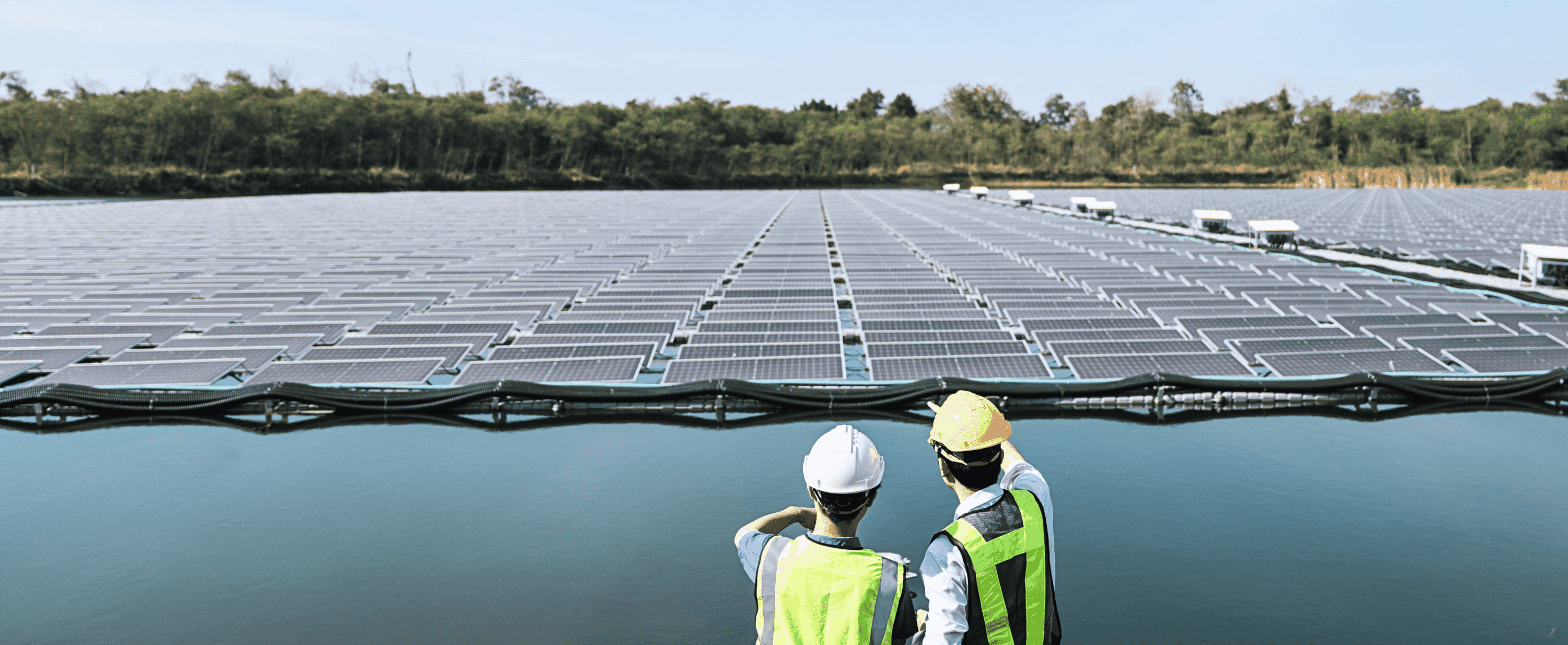 Zwei Arbeiter beraten sich über die schwimmende PV-Anlage auf dem Wasser vor ihnen