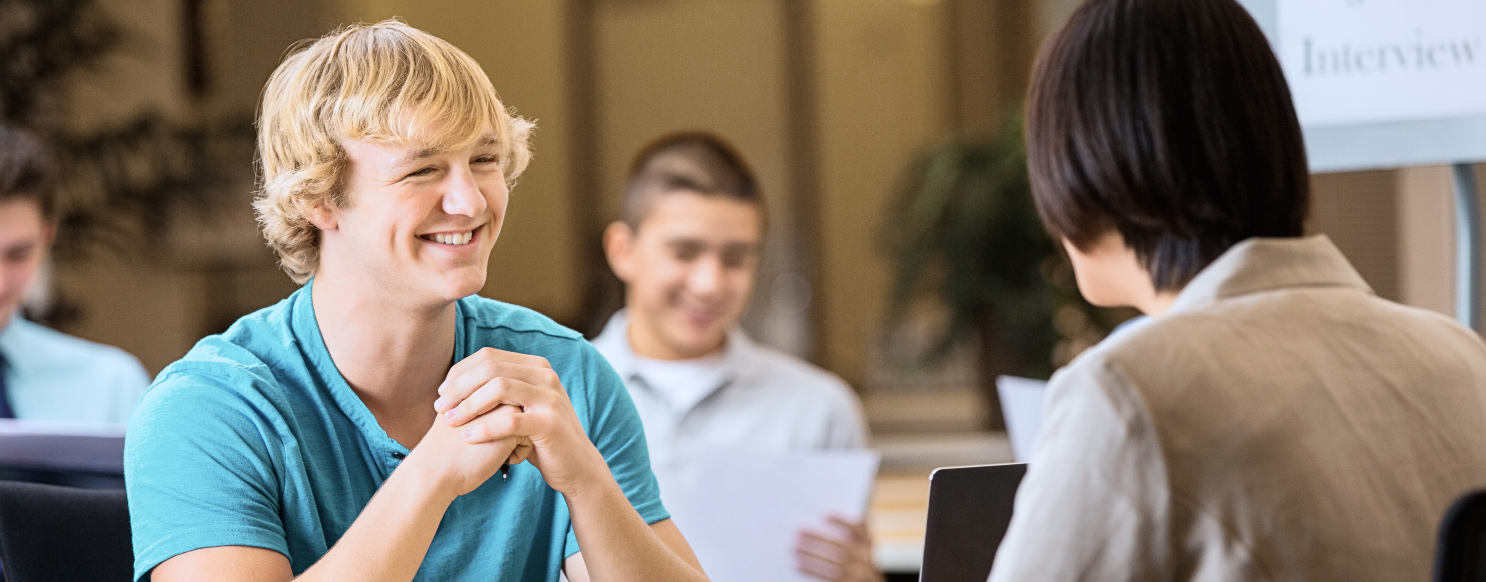 Junger Mann sitzt lächelnd im Jobinterview Junger Mann sitzt lächelnd im Jobinterview