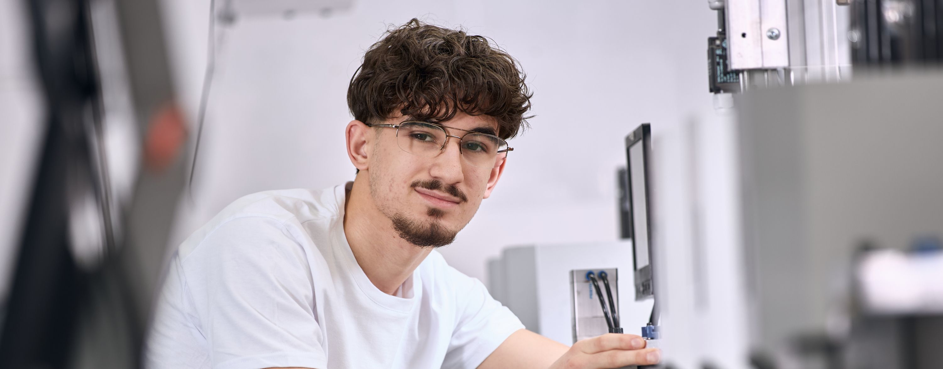 Junger Mitarbeiter arbeitet an einer Maschine Junger Mitarbeiter arbeitet an einer Maschine