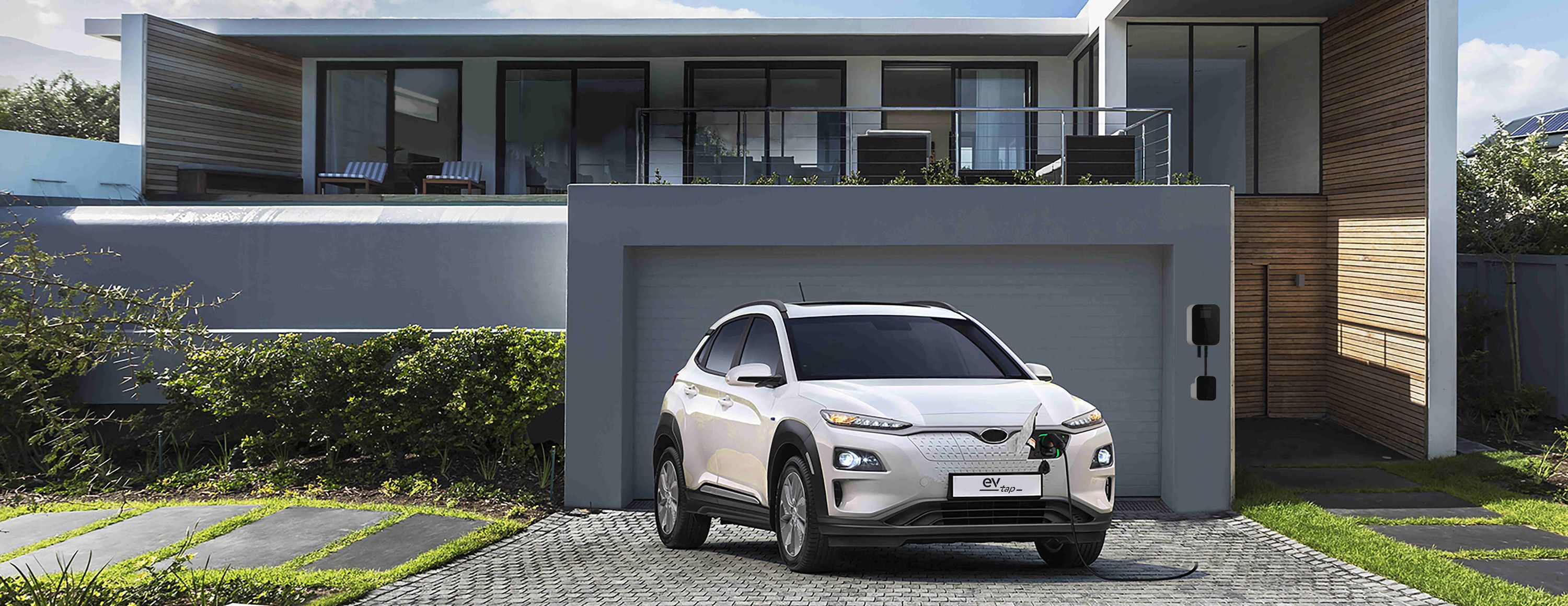 Ein Auto steht in der Einfahrt und lädt mit einer eigenen Home Ladestation