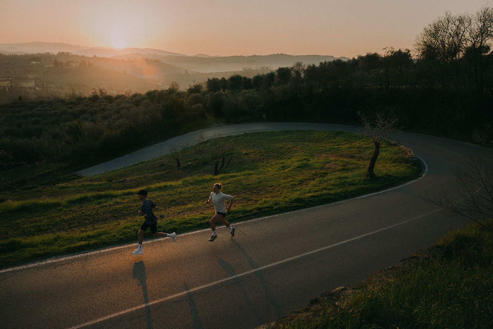 To som løper oppover en bakke på asfalt