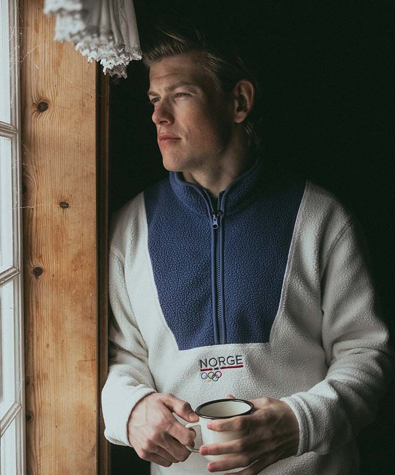 Johannes Høsflot Klæbo med en kopp i hånda, står ved et vindu