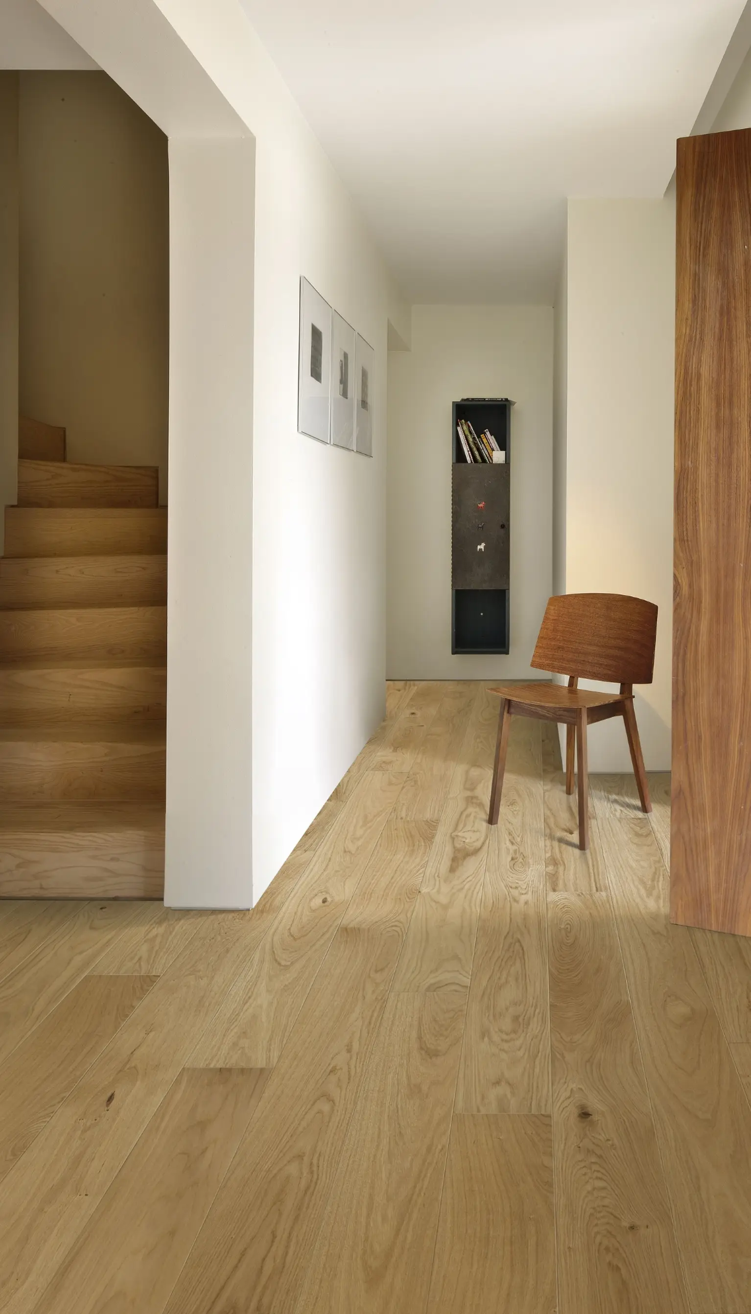 A minimalist hallway with warm oak flooring, wooden furniture, and neutral decor.